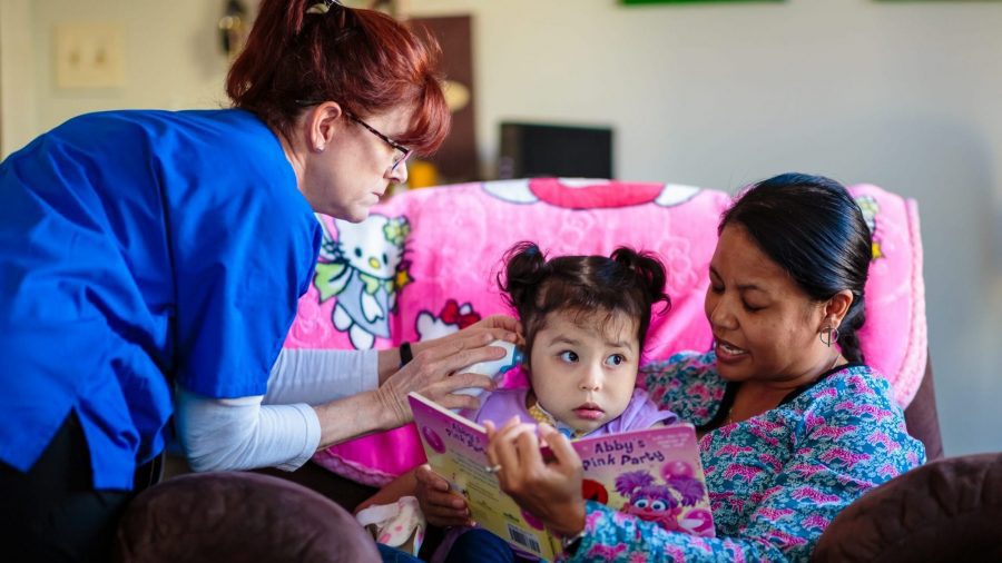 two nurses reading with little girl
