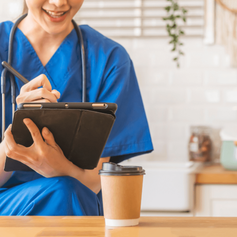 nurse in blue scrubs holding an iPad