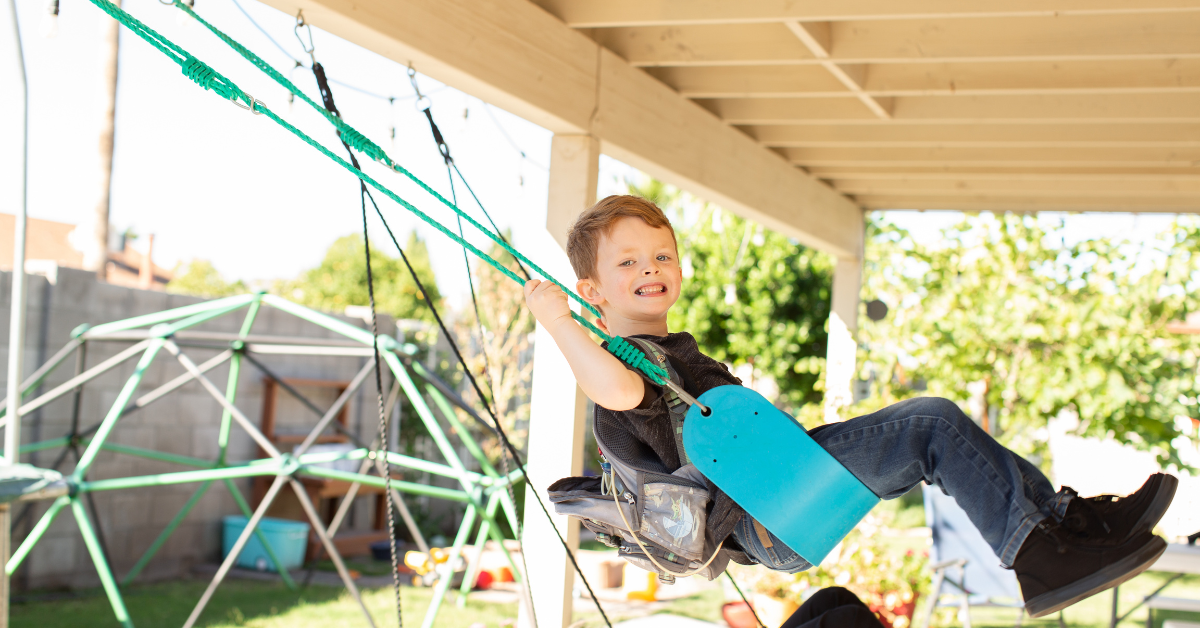 a boy smiling while on a swing