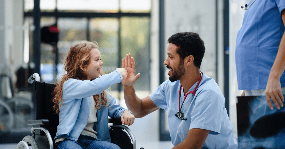 nurse high-fiving a patient in wheelchair - How Pediatric Home Care Nurses Can Help Patients Gain Independence